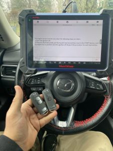 An automotive locksmith coding a new Mazda key fob on-site
