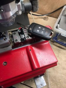 Automotive locksmith cutting a new transponder flip key (Chevy)