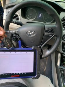 An automotive locksmith coding a new transponder flip key on-site (Hyundai)