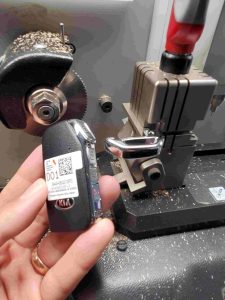 Automotive locksmith cutting a new Kia key fob