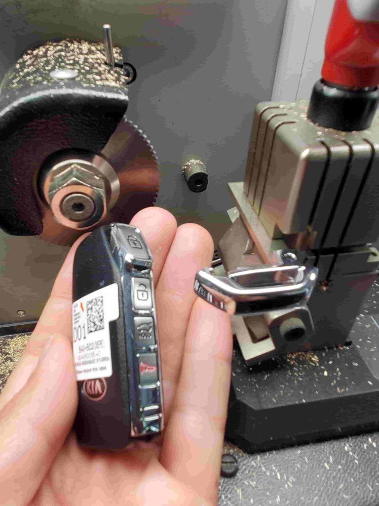 A locksmith is cutting a new Kia key