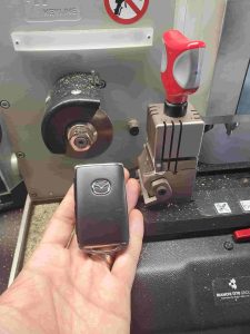 Mazda key fob and emergency key on cutting machine by an automotive locksmith