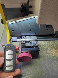 Automotive locksmith is cutting a Mazda key fob emergency key