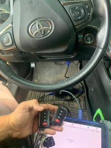 An automotive locksmith coding a new Toyota key fobs on-site