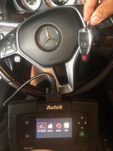 Automotive locksmith coding a new Mercedes key fob on-site with a programming machine